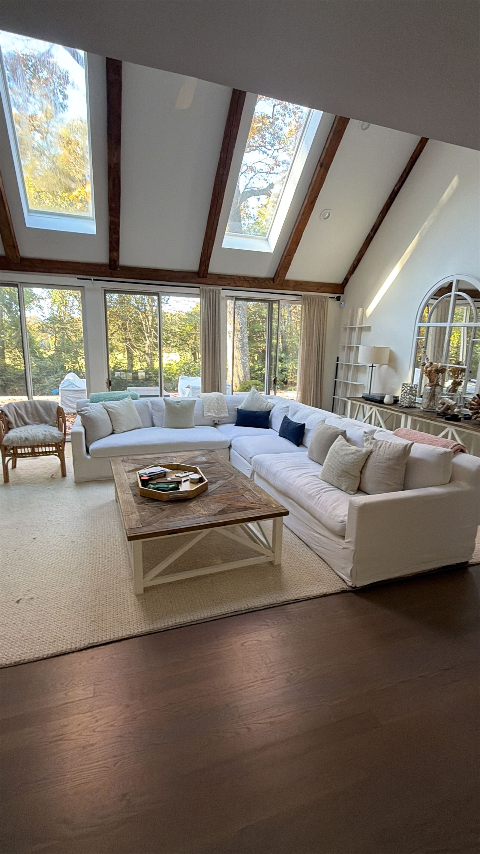Bright vaulted living room with white sofas and skylights after a cleaning